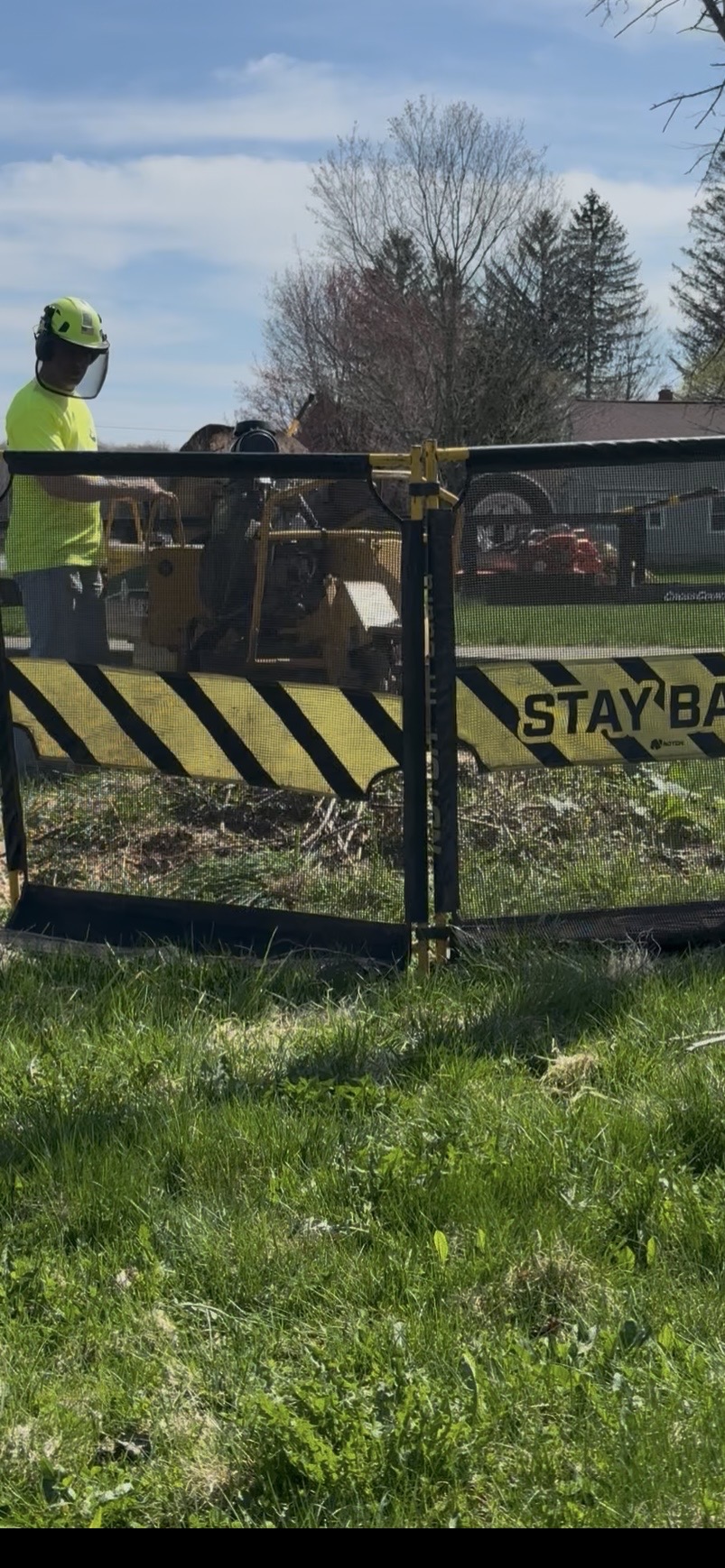 5D Stump and Tree technician operating stump grinder behind NOTCH TRIGUARD safety mesh panel